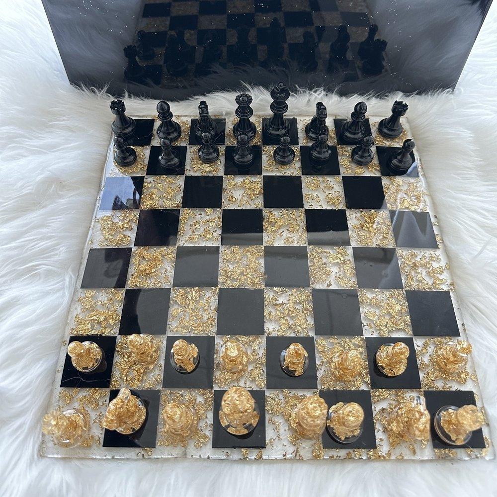 
"Top view of a handcrafted chess board featuring a glossy epoxy resin finish with alternating dark and light squares. The chess board's smooth, polished surface reflects light, highlighting intricate details in the resin pattern. The wooden edges frame the board, providing a warm contrast to the sleek resin, blending art and functionality seamlessly."