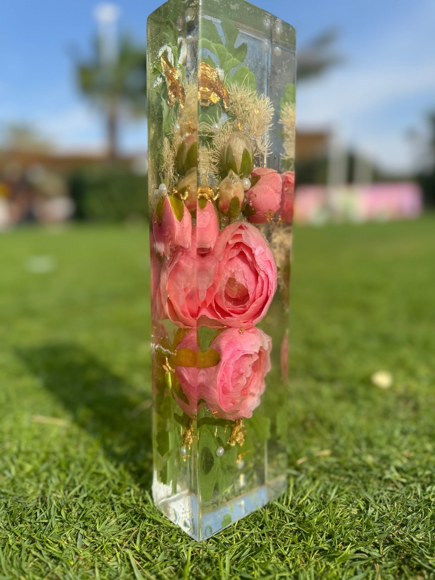 Rectangle resin block with preserved roses and flowers by Hyacinth Resin Arts, displayed on grass, showcasing vibrant blooms encased in a glossy epoxy resin finish.