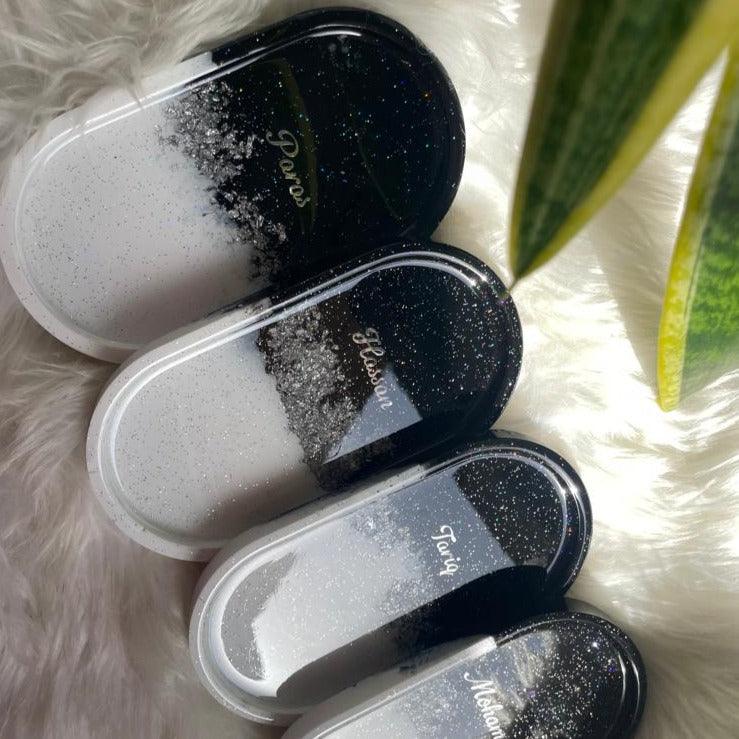 "Top view of four trinket trays arranged closely together on a soft white surface, each featuring a consistent black and white color scheme with distinct resin patterns."