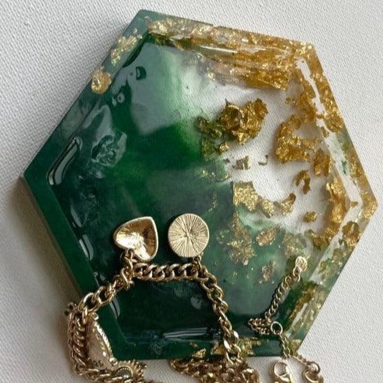 "Resin trinket tray in a pentagon shape, featuring a geode theme with green and gold colors, complemented by a chain attached for decorative flair."