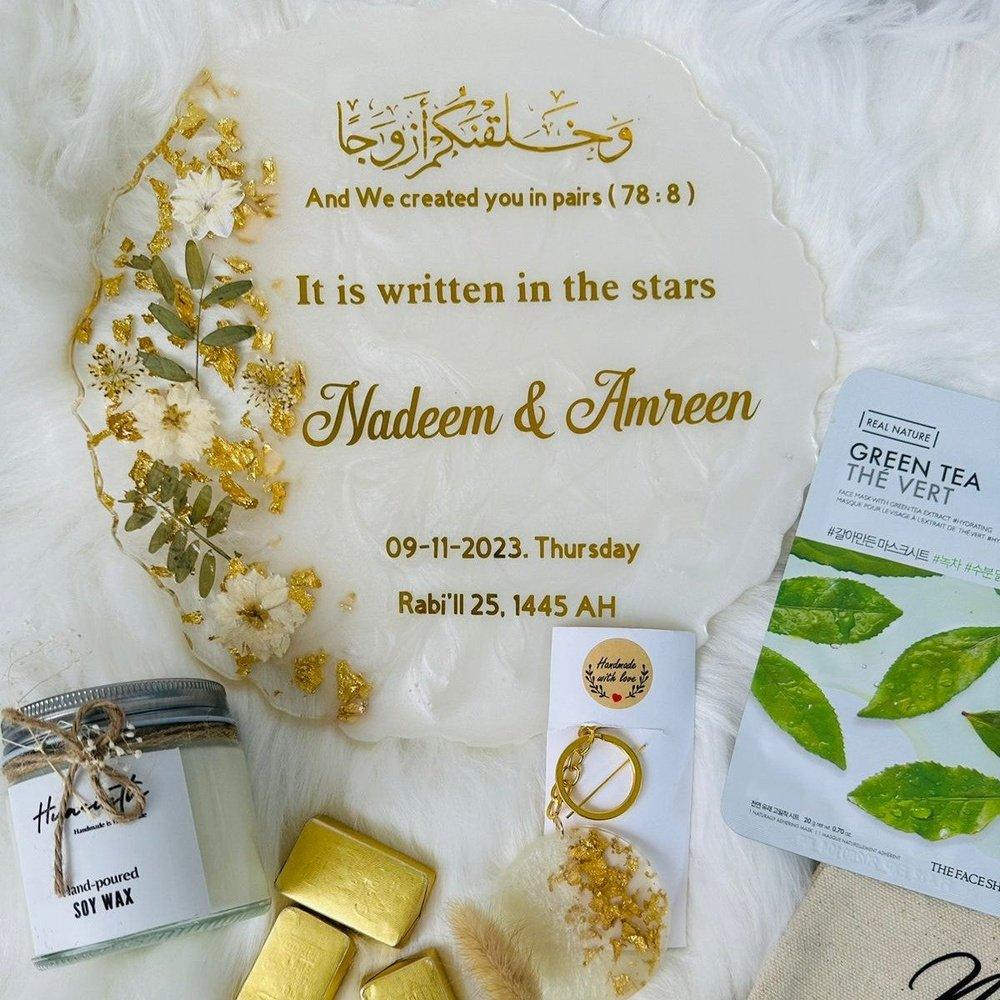 "Top view of items from a Wedding/Anniversary Box artfully arranged on a white, feather-like surface, showcasing their elegant designs and fine craftsmanship."