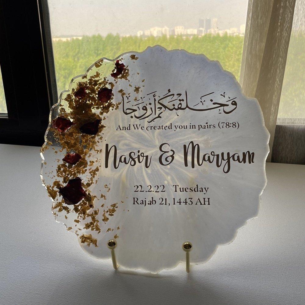 "Front view of a wedding and anniversary resin coaster on a gold-plated stand, positioned next to a window, showcasing its elegant design in natural light."