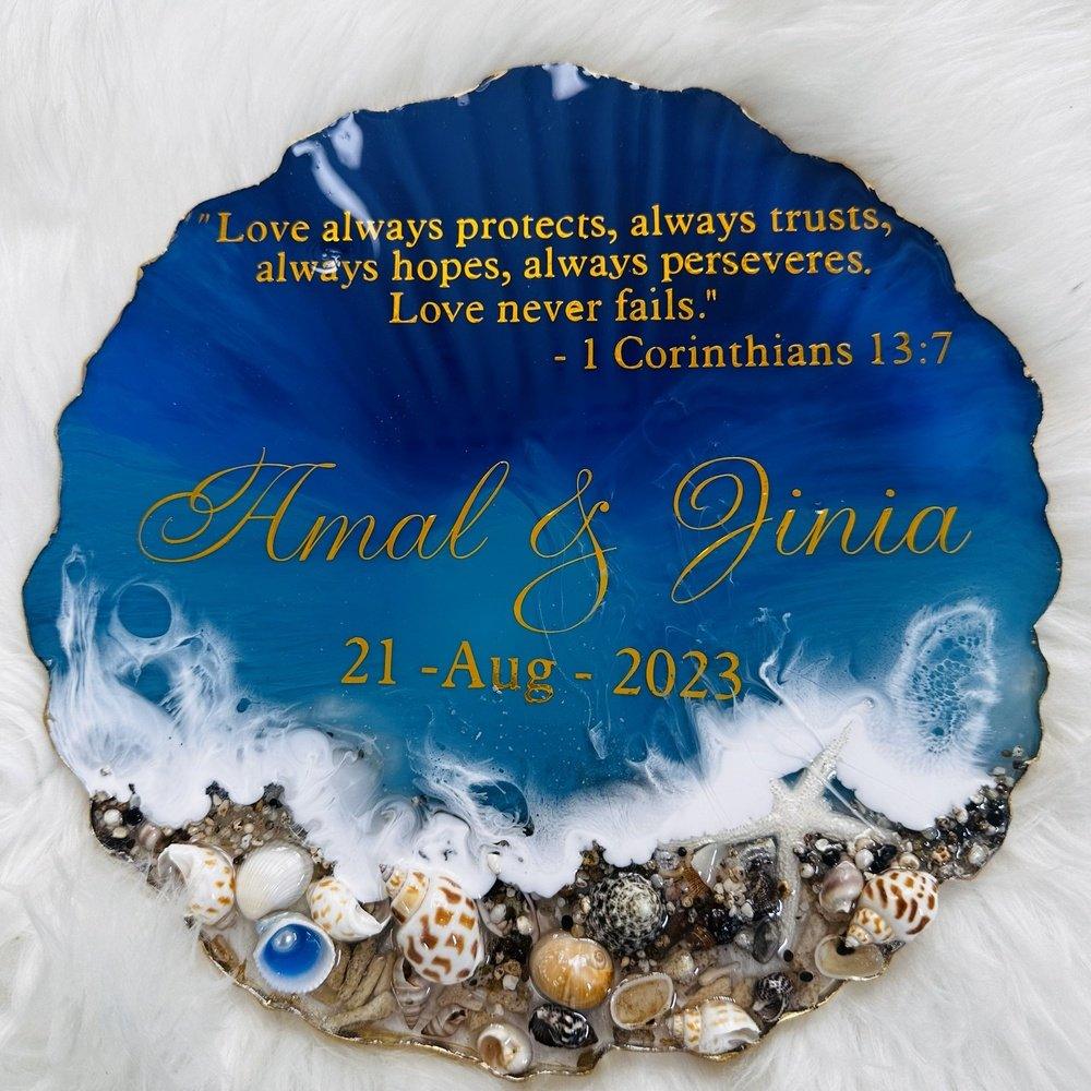 "Top view of an ocean-themed wedding and anniversary resin coaster, set on a soft white, feather-like surface, displaying serene blue tones and wave-like patterns."